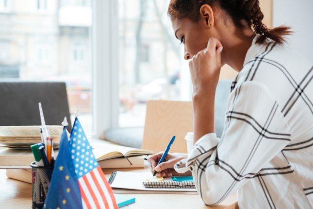 Woman preparing for green card application at desk with miniature American flag.